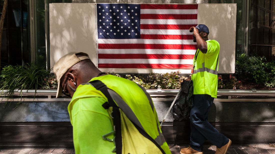 Street cleaners pass by the American flag in Charlotte on Sunday.