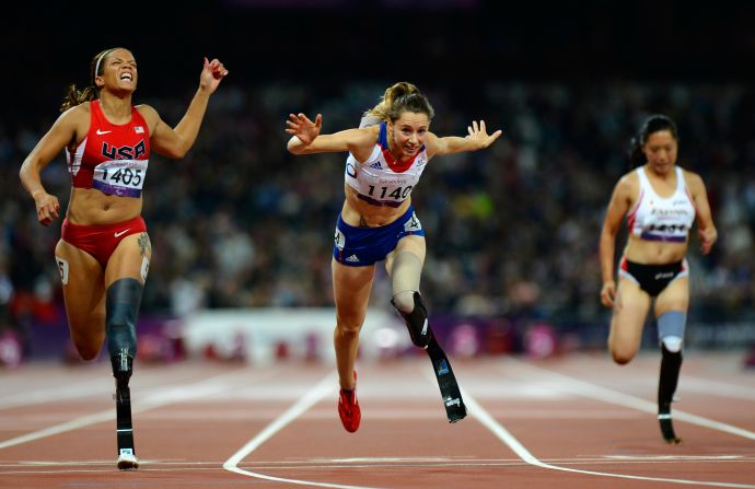 France's Marie-Amelie le Fur, center, lunges over the finish line to win the women's 100-meter T44 final as  April Holmes, left, of the United States finishes third.