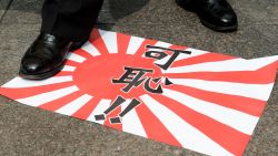 A Hong Kong activist steps on a paper replica of the Japanese imperial flag reading 'shameful' before burning it during a demonstration outside the building containing Japan's consulate in Hong Kong on August 24, 2012.  About a dozen people handed a letter over to a representative from the consulate in protest about the ongoing dispute over a group of islands, known as the Senkakus in Japanese and the Diaoyus in Chinese. Japan on August 17 deported a group of pro-Beijing activists back to Hong Kong just 48 hours after some of the 14 had become the first non-Japanese to set foot on any part of the disputed archipelago since 2004.