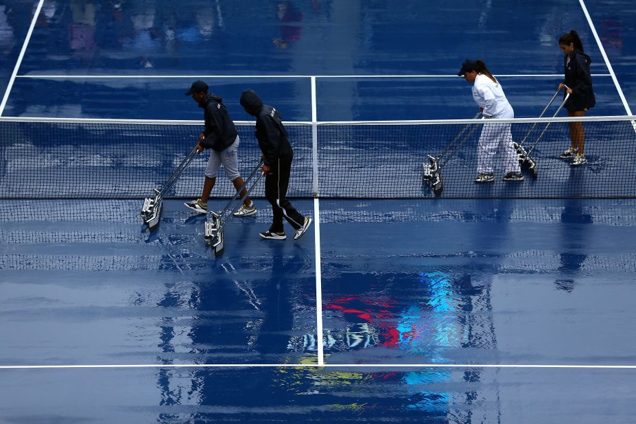 A grounds crew dries the court Tuesday after rain suspended play. 
