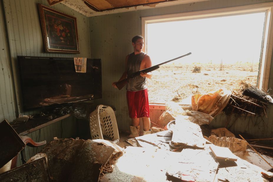 Eric DeSalvo salvages a gun Monday from the flooded Martinez home in Braithwaite, Louisiana.