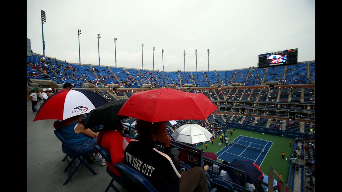 Spectators shelter under umbrellas as rain delays play during the women's singles quarterfinal match between Maria Sharapova of Russia and Marion Bartoli of France on Tuesday.