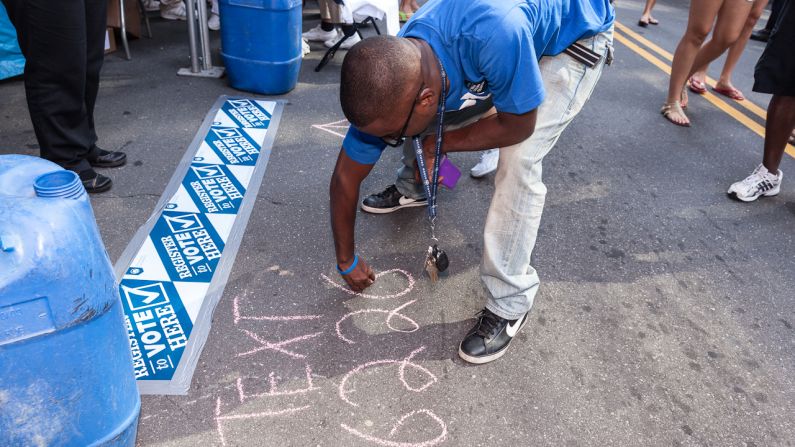 A man writes in chalk to promote a voter registration booth during the DNC on Monday.