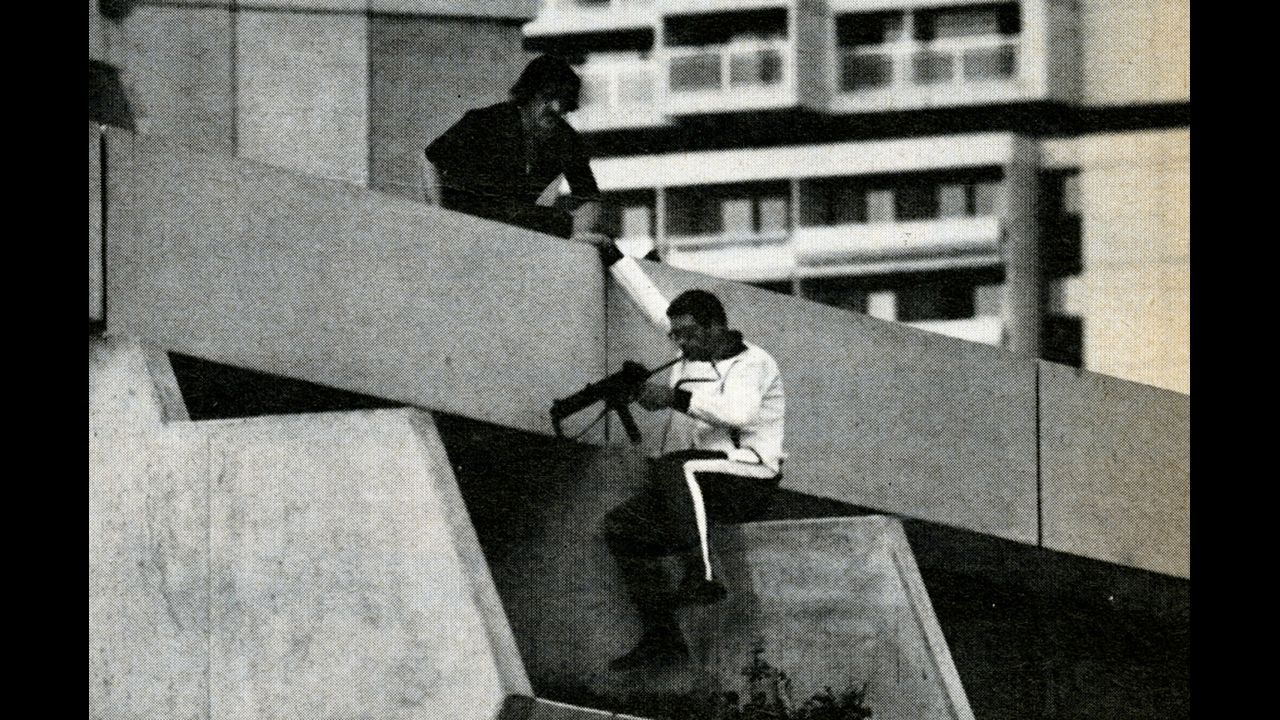 Perched on a terrace directly above the Israeli quarters, a German policeman checks his submachine gun before advancing further, Munich, September 1972.