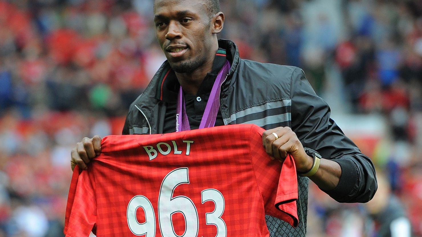 Usain Bolt shows off a special Manchester United shirt bearing his winning time in the 2012 Olympic 100m final.