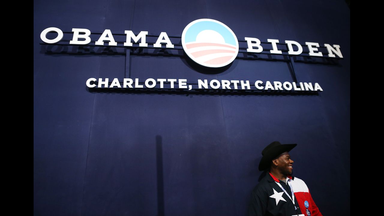 A man from the Texas delegation stands under a campaign sign.