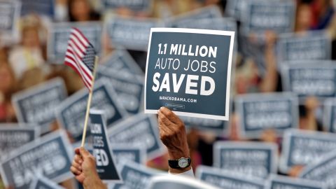 Audience members wave signs Wednesday in support of the American auto industry.