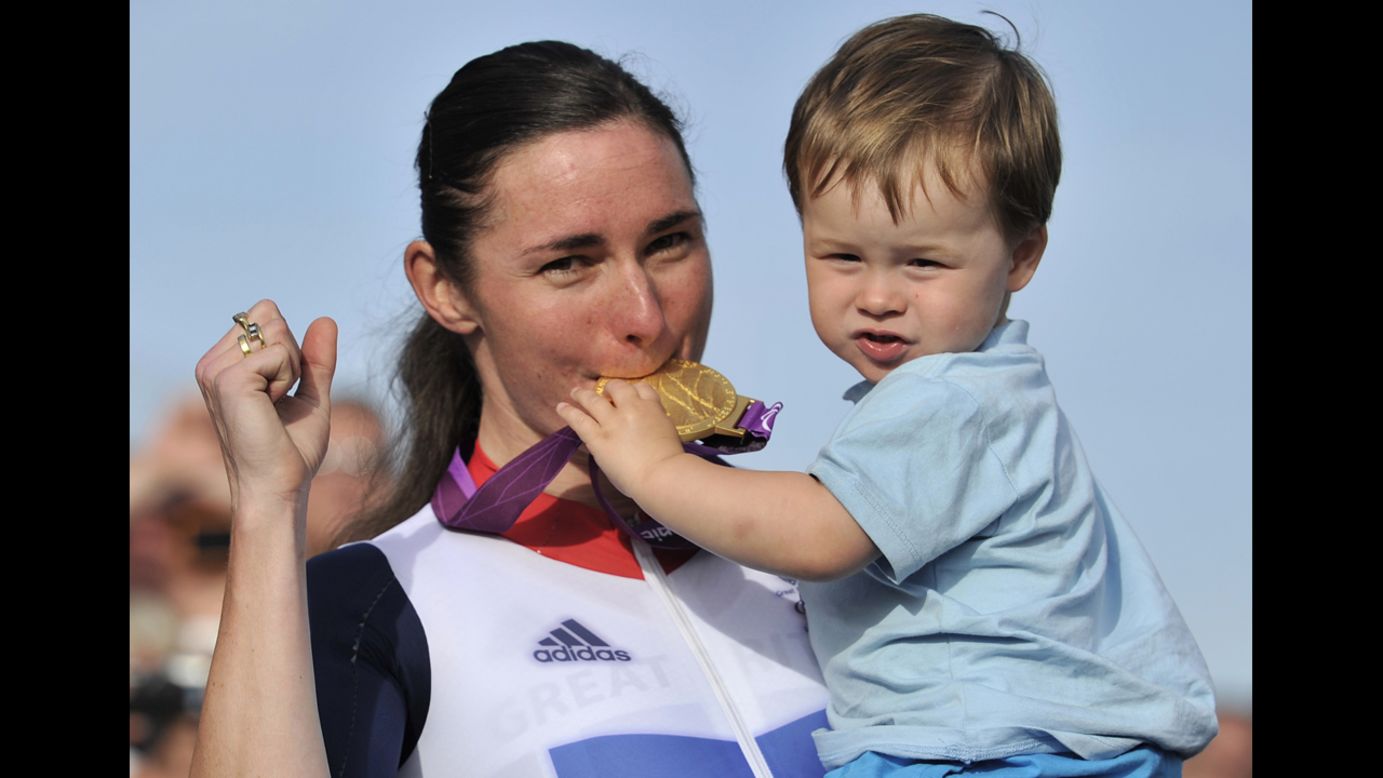 Britain's Sarah Storey, left, bites her gold medal as her nephew Gethin Crayford holds it on the podium after she won the women's individual C4-5 road race cycling final on Thursday.