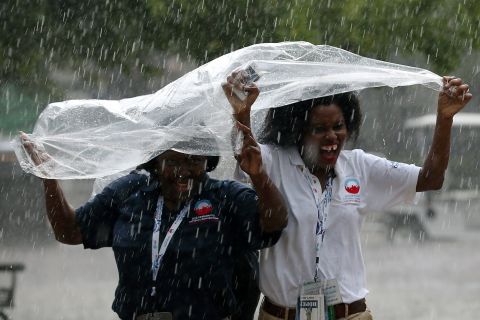 Two women run for cover from the pouring rain during the final day of the convention on Thursday.