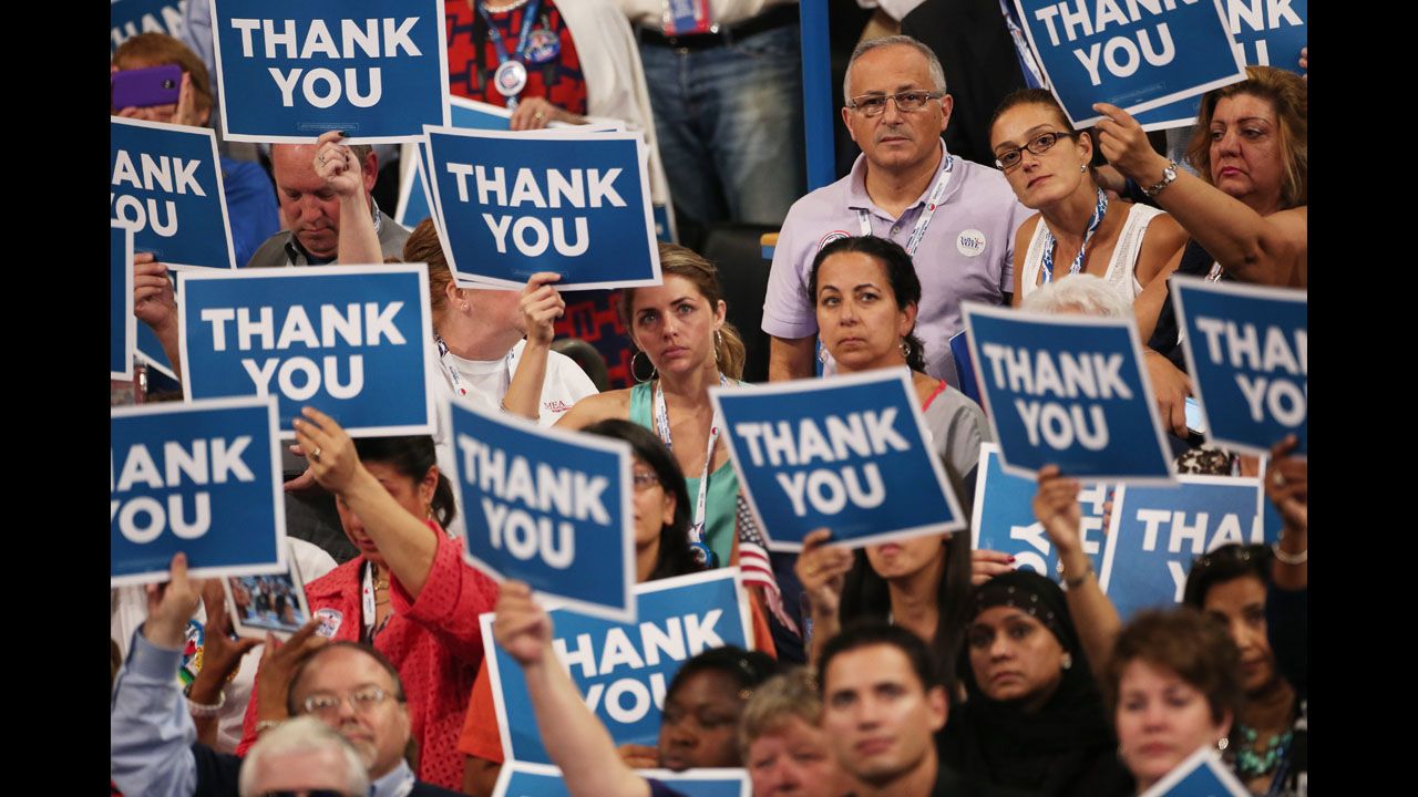 Attendees hold signs that say "Thank You" for miltary veterans on Thursday.