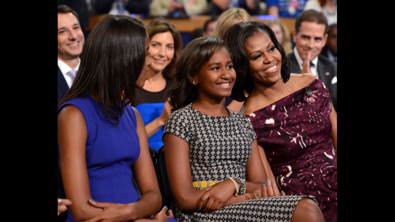 First lady Michelle Obama, with daughters Malia, left, and Sasha, smiles as Barack Obama delivers his acceptance speech on Thursday.