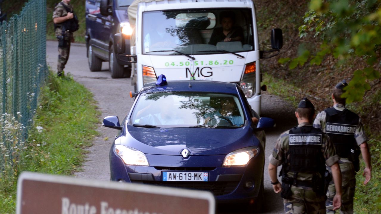 A tow truck escorted by French gendarmes on the 'Combe d'Ire' road carries the car in which three people were shot dead on September 6, 2012 in the French Alpine village of Chevaline. A four-year-old girl spent hours curled up under her mother's body and miraculously survived the deadly attack that left her father, mother and grandmother dead and her elder sister seriously injured, officials said