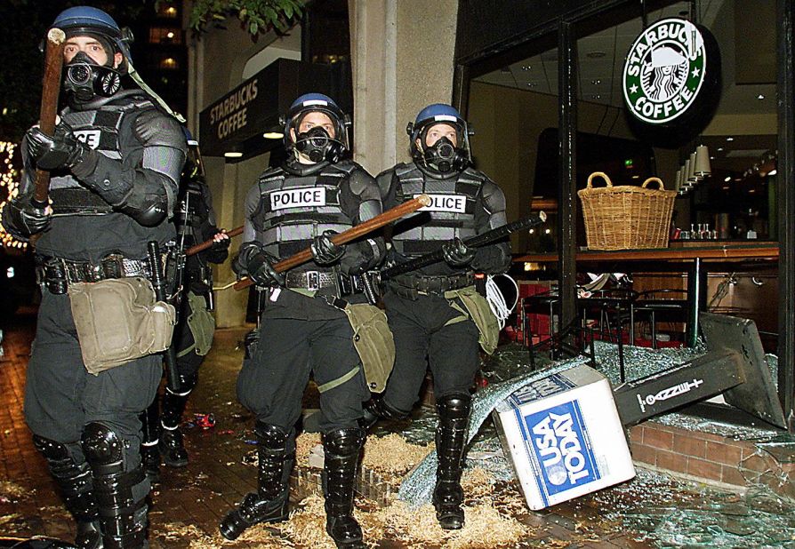 <strong>1999:</strong> Riot police march past a damaged Starbucks coffee shop during demonstrations against the World Trade Organization Summit in Seattle on November 30, 1999. Thousands of activists aimed to disrupt the WTO. 