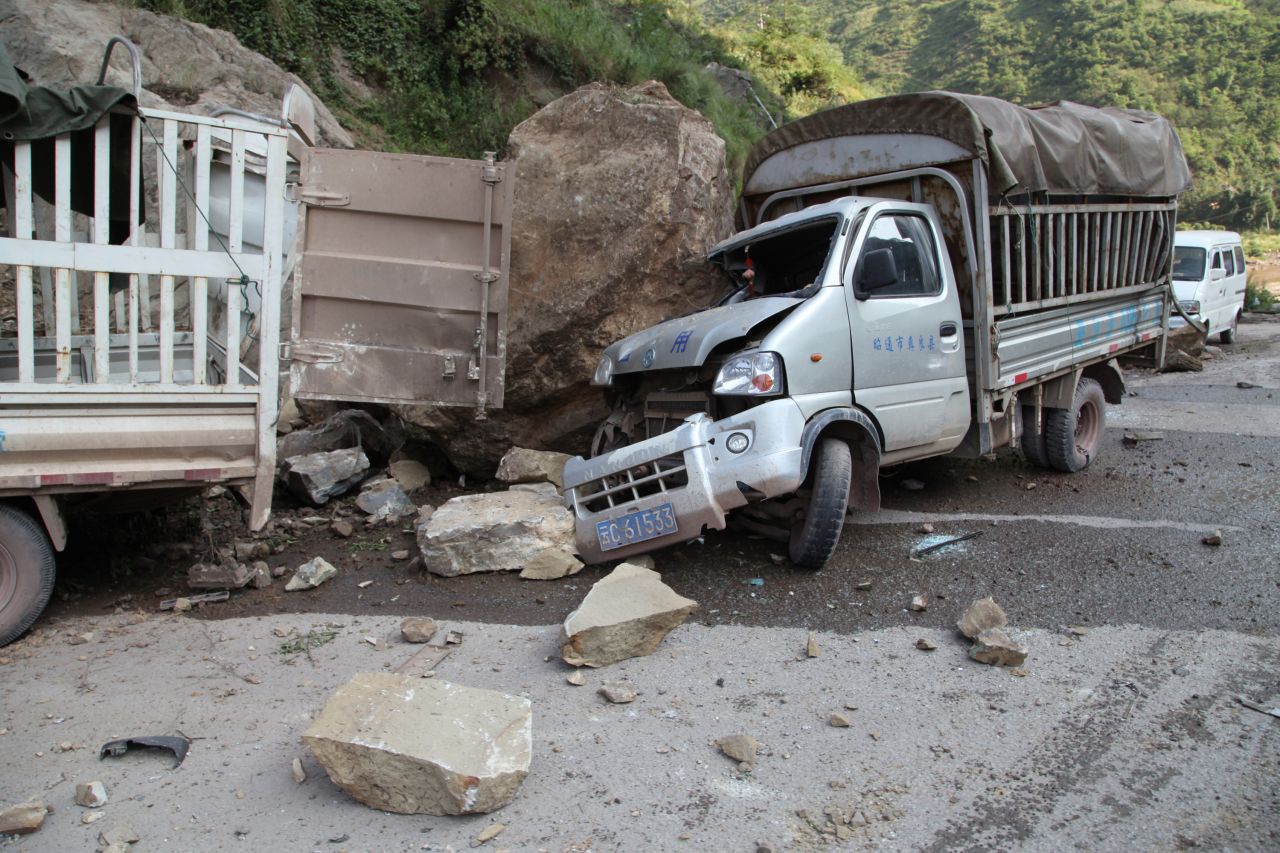 Damaged vehicles sit at a roadside in Yiliang.