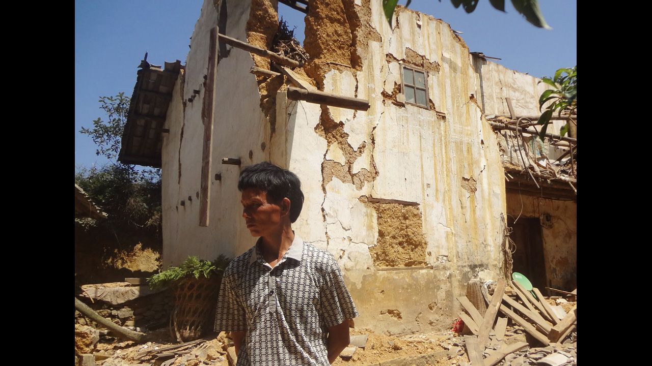 A man stands in front of a damaged house in Xinlong Village of Weining County, in Guizhou province.