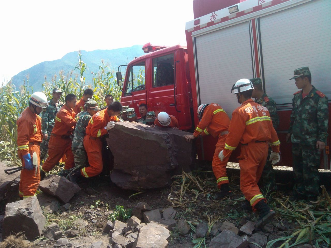 Rescuers remove a rock from a road in Yiliang.