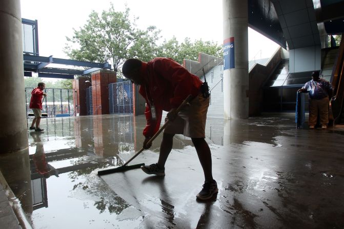 Grounds crew workers clear water during a rain delay on Saturday.