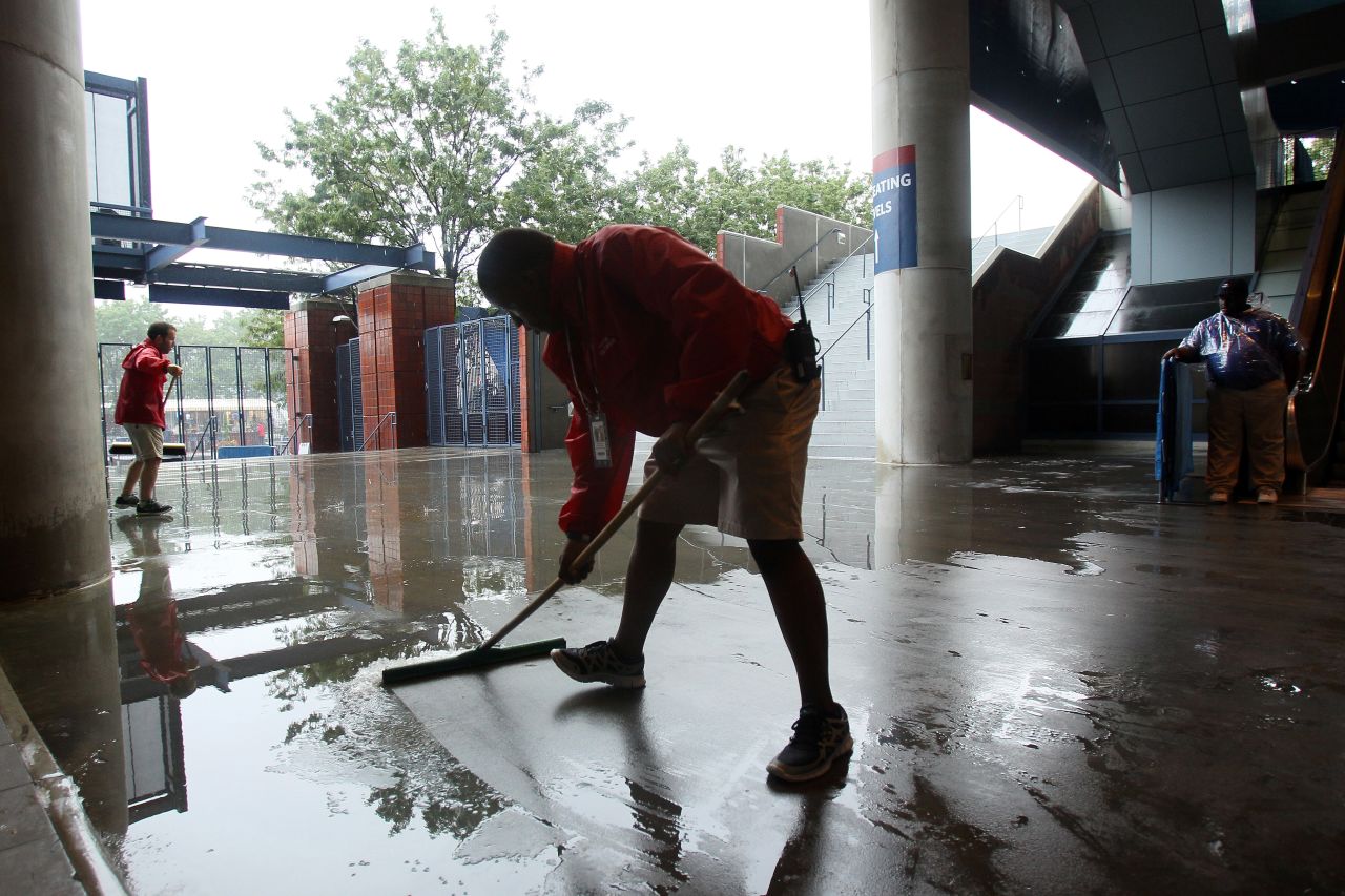 Grounds crew workers clear water during a rain delay on Saturday.