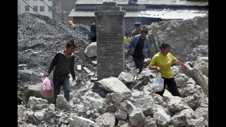 Survivors make their way through the rubble of a collapsed home on Saturday.