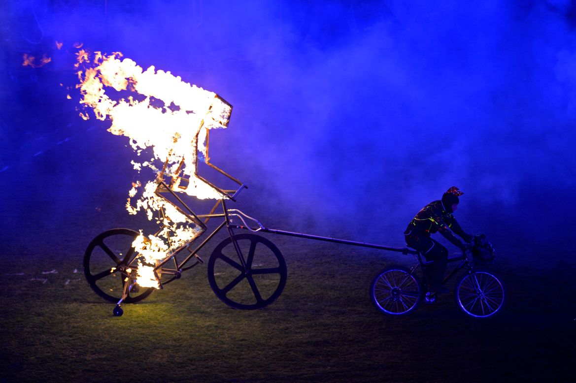 A flaming figure of a cyclist enters the arena.