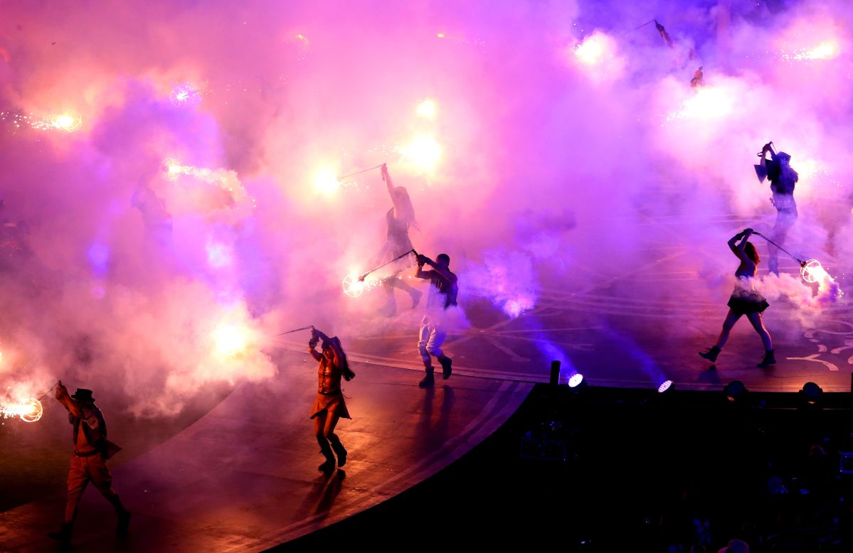 Smoke and flames fill the air as dancers perform.
