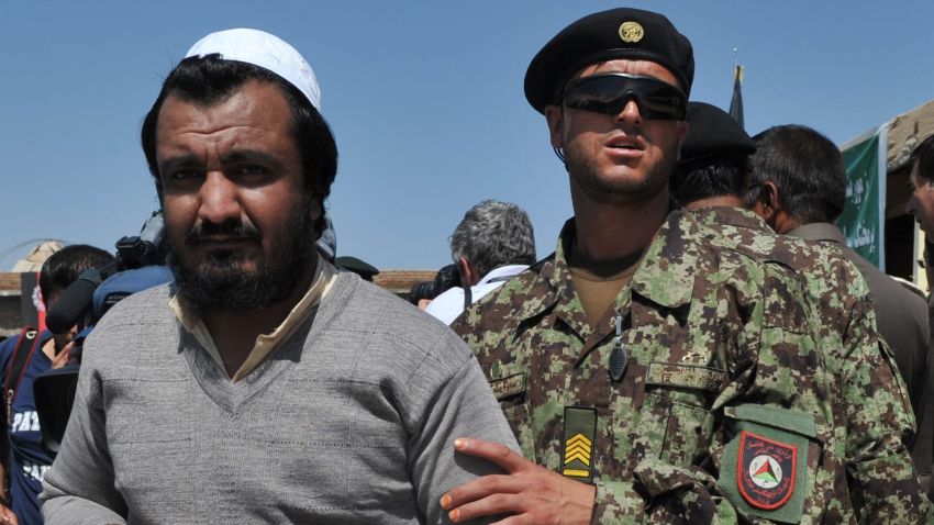 An Afghan National Army soldier escorts a newly-freed prisoner after a ceremony handing over the Bagram prison to Afghan authorities.