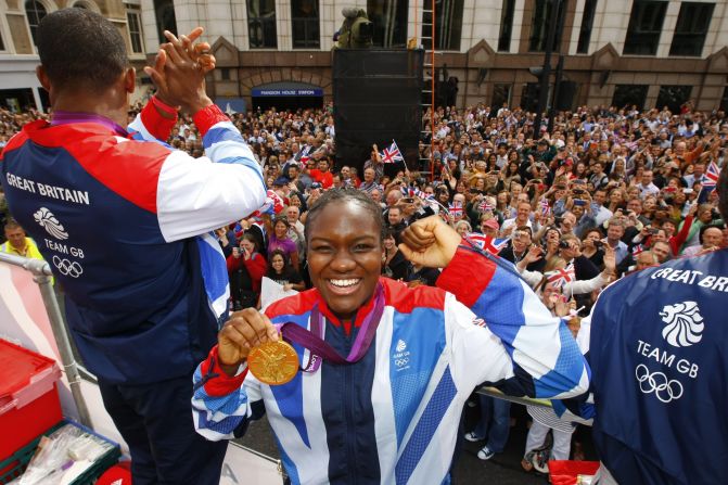 Olympic boxer Nicola Adams smiles as she holds up her gold medal for the camera.