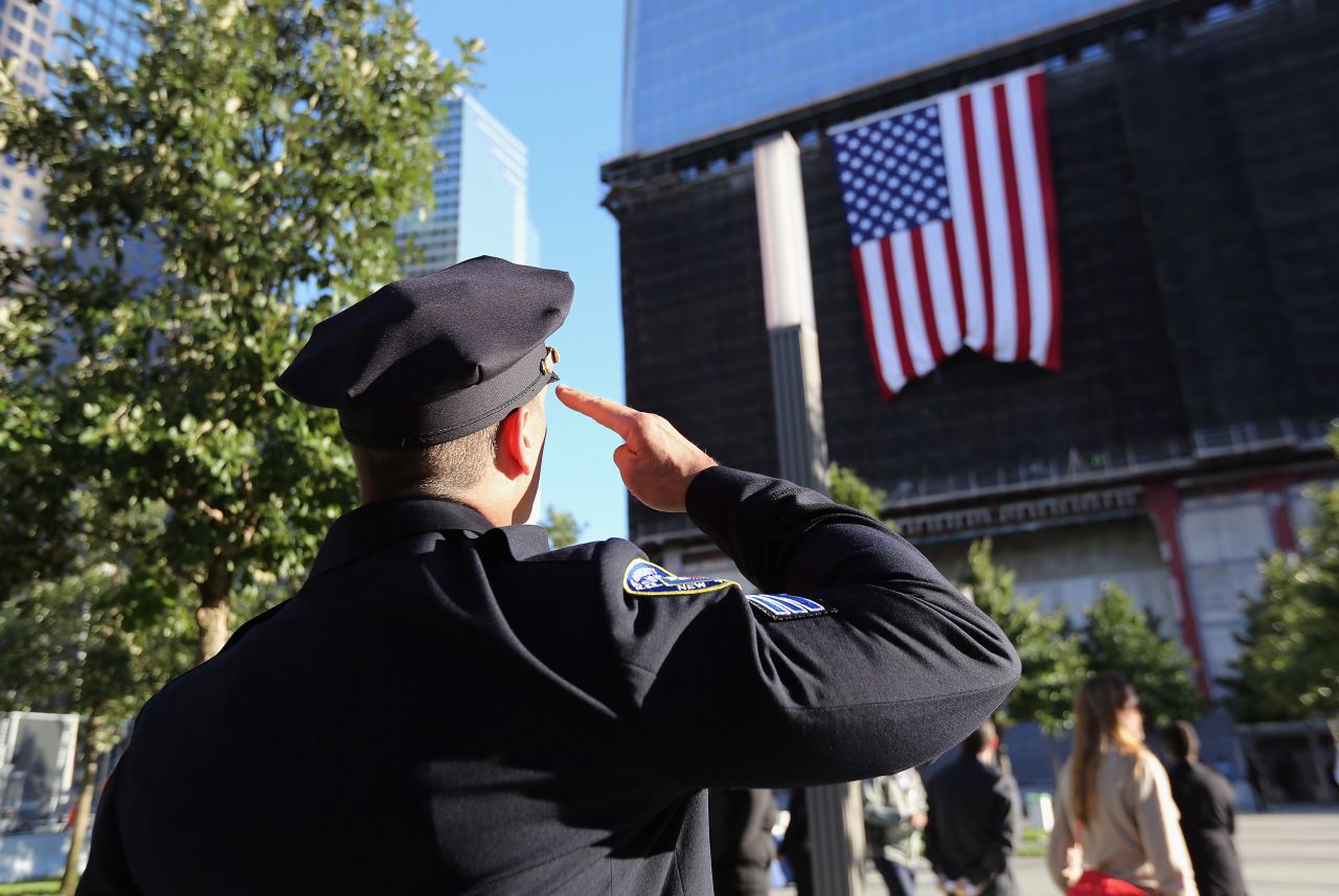 A New York City police officer salutes a flag hanging from One World Trade on Monday.