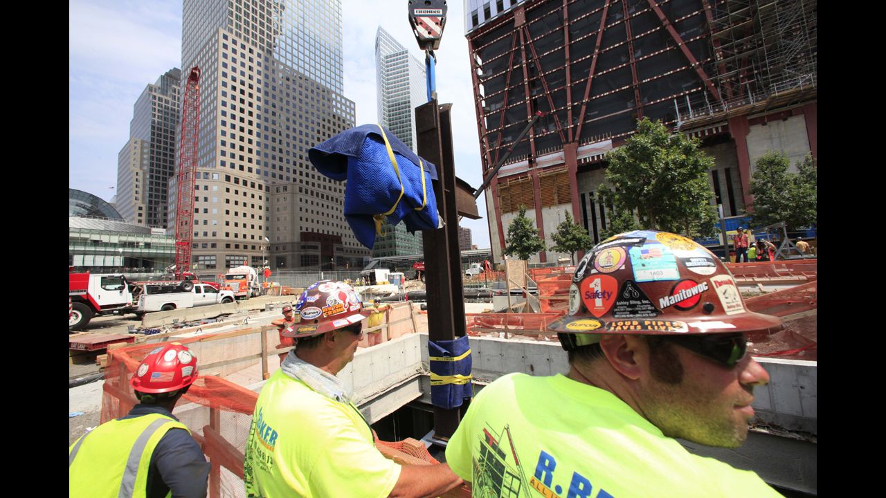Construction workers watch as the cross is lowered by crane into a subterranean section of the 9/11 Memorial and Museum on July 23, 2011.