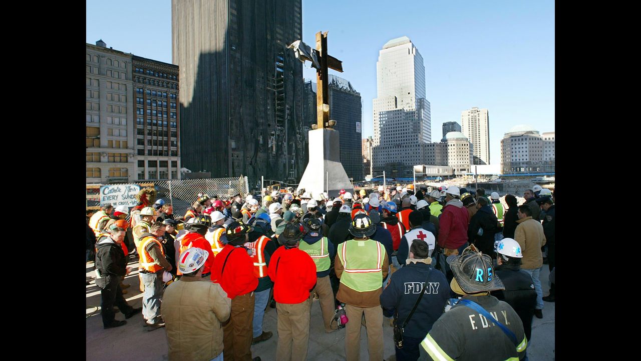 New York City firefighters and construction workers surround the steel cross at Ground Zero during a prayer service held at 8:46 am to commemorate the sixth-month anniversary of the September 11 terrorist attacks on March 11, 2002 in New York City.