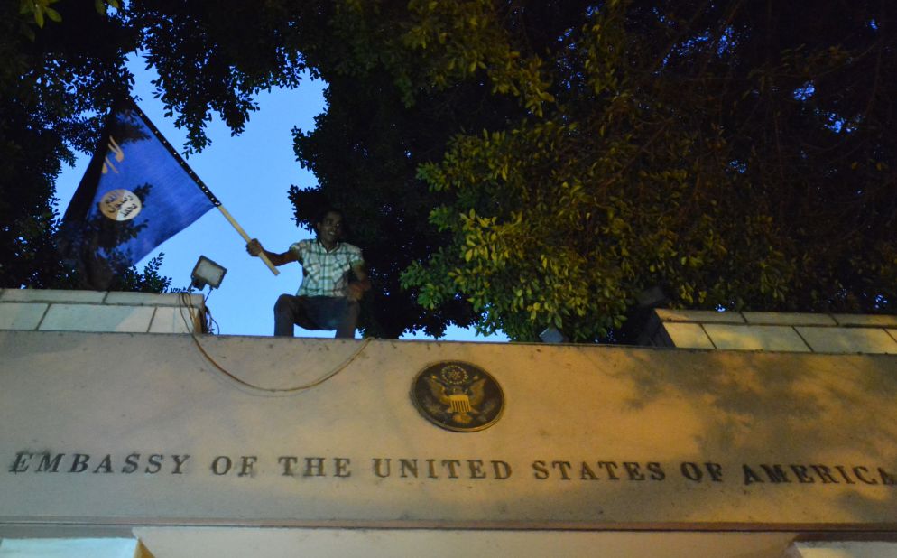 An Egyptian protester waves a black flag inscribed with the Muslim profession of faith -- "There is no God but God, and Mohammed is the prophet of God" -- as he stands above the door of the U.S. Embassy.