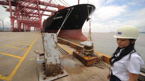 A worker at the Ningbo Port stands beside a container ship wating to be loaded in Ningbo on June 21, 2012.