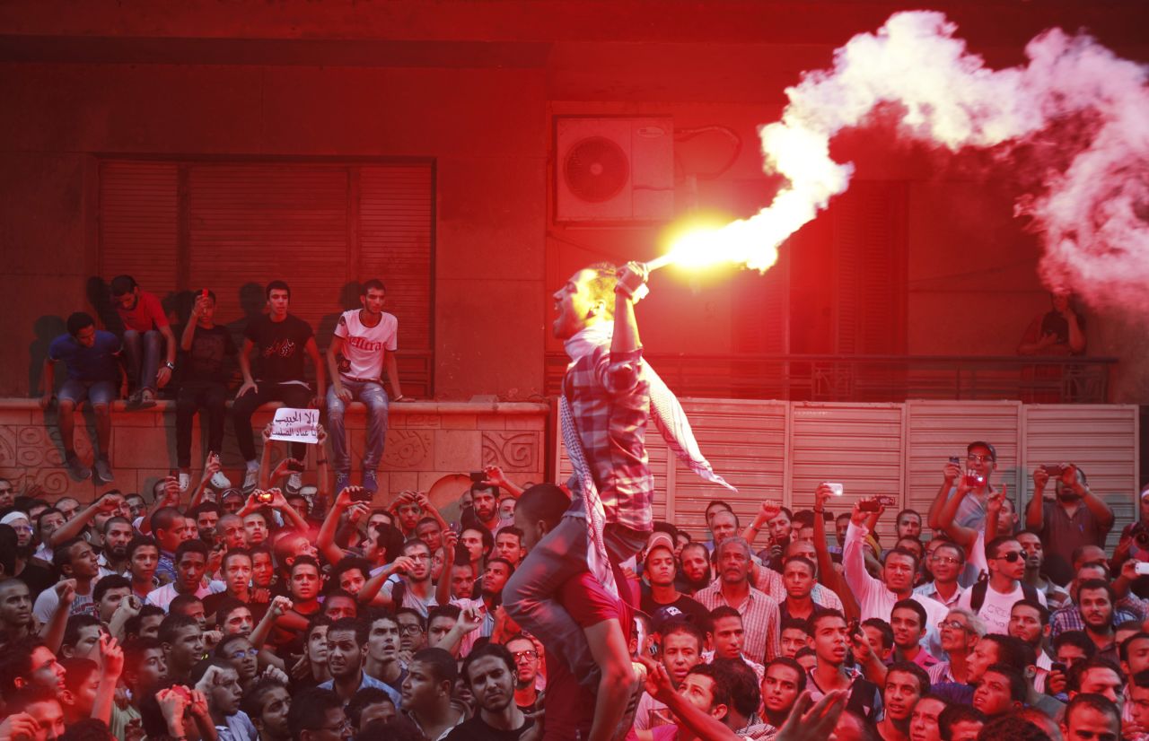 People shout and light flares in front of the U.S. Embassy in Cairo.