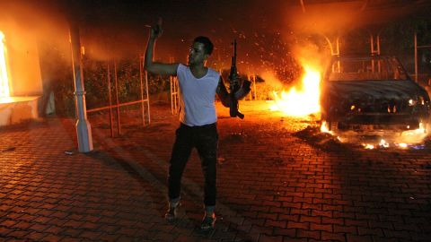 A man waves his rifle as buildings burn during protests at the U.S. consulate compound in Benghazi late Tuesday.