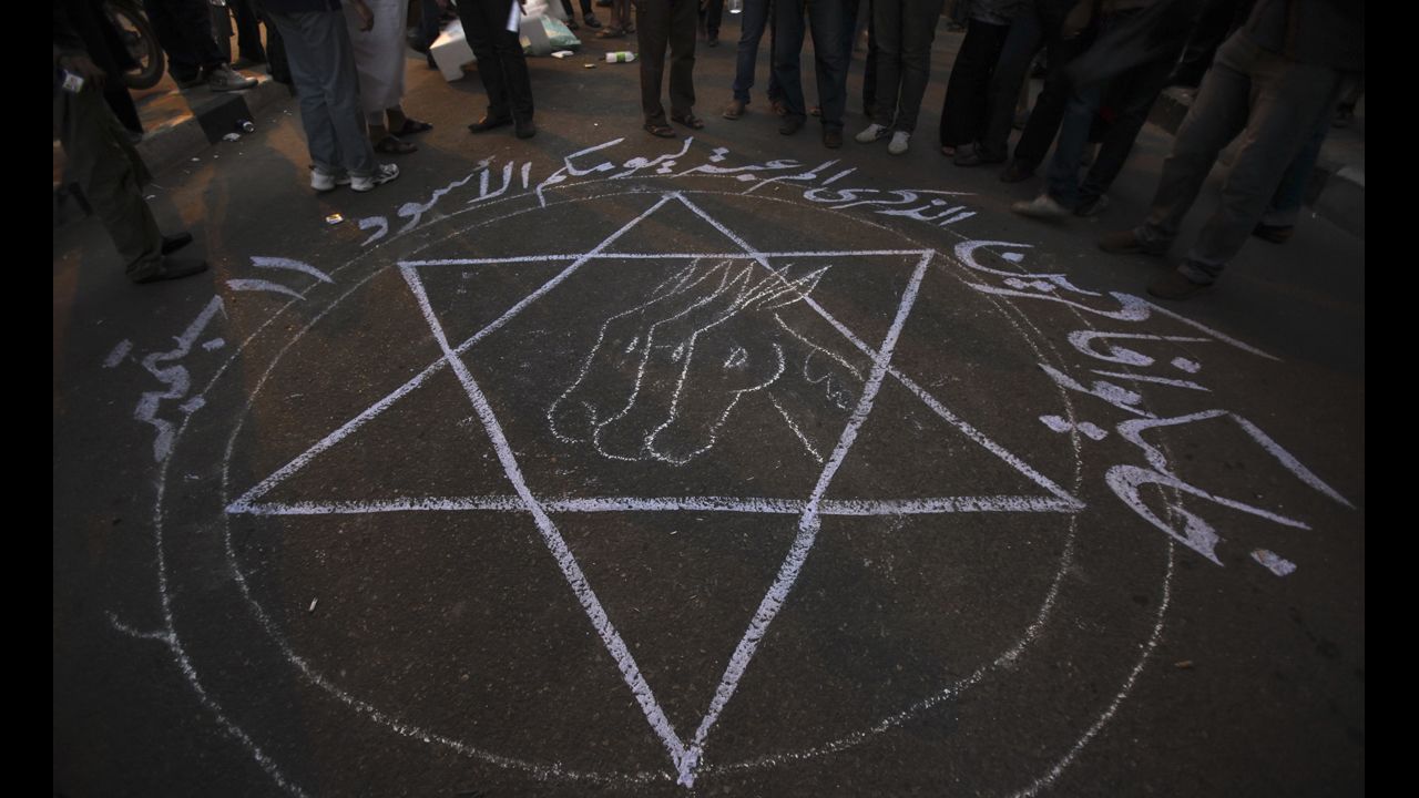 People stand around a drawing that says "Remember your black day 11 September" during the protest in Cairo.