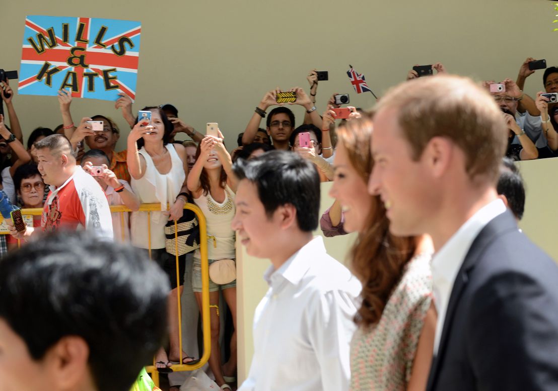 Bystanders crane for photos of the Duke and Duchess of Cambridge during their visit to Strathmore Green, a precinct in Queenstown, a residential district of Singapore on Wednesday.