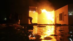People duck flames outside a consulate building on Tuesday.