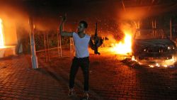 An armed man waves his rifle as buildings and cars are engulfed in flames after being set on fire inside the US consulate compound in Benghazi late on September 11, 2012. 