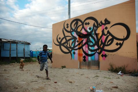 During a recent visit to Cape Town, eL Seed defied advice to visit a township and paint on the wall of a newly constructed daycare building. He said there was a lot of debate among locals about his decision to write in Arabic. The words mean "It is impossible unitl it is done."
