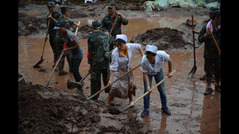 Nurses join soldiers to clear mud and debris from the hospital on Monday.