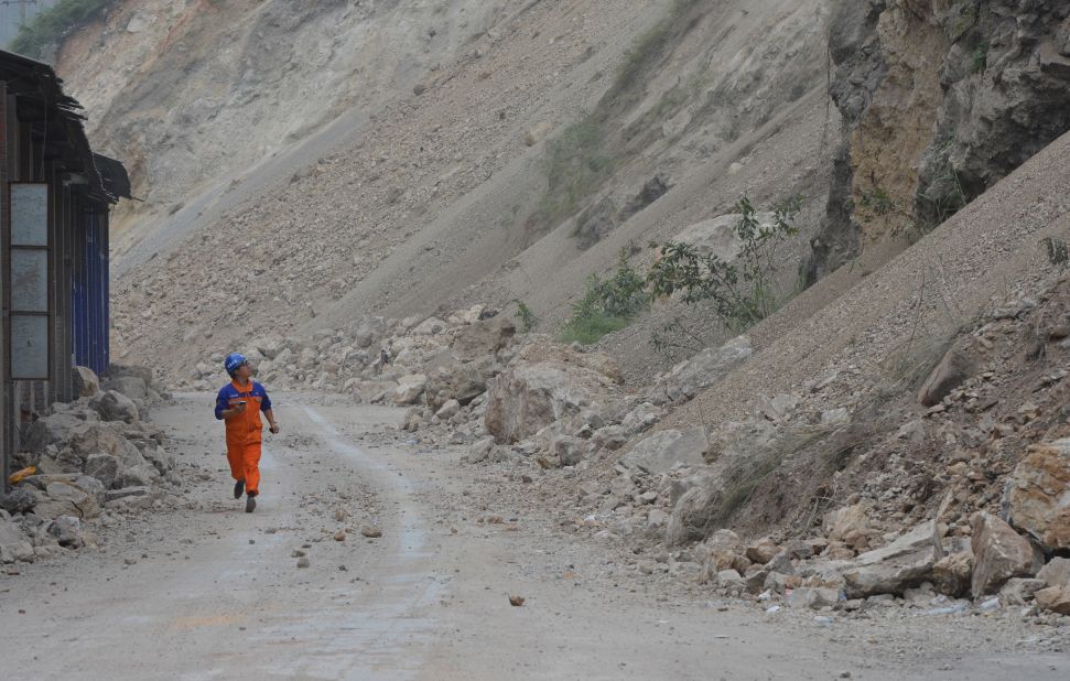 A man runs past a landslide area on Monday as high winds cause rocks to continue falling days after the earthquakes.