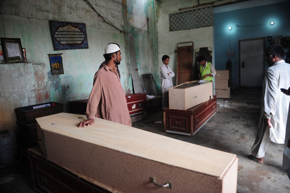 Pakistani men wait alongside coffins for the bodies of their relatives who died in the garment factory fire.