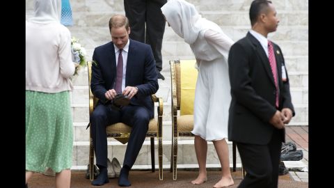 The royal couple put their shoes on after visiting the KLCC Mosque in Kuala Lumpur on Friday.
