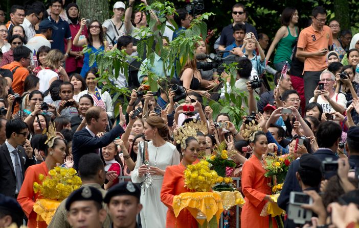 A crowd takes photos of Prince William and Catherine, Duchess of Cambridge, as they walk in the KLCC gardens in Kuala Lumpur on Friday.