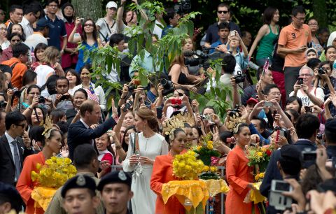 A crowd takes photos of Prince William and Catherine, Duchess of Cambridge, as they walk in the KLCC gardens in Kuala Lumpur on Friday.