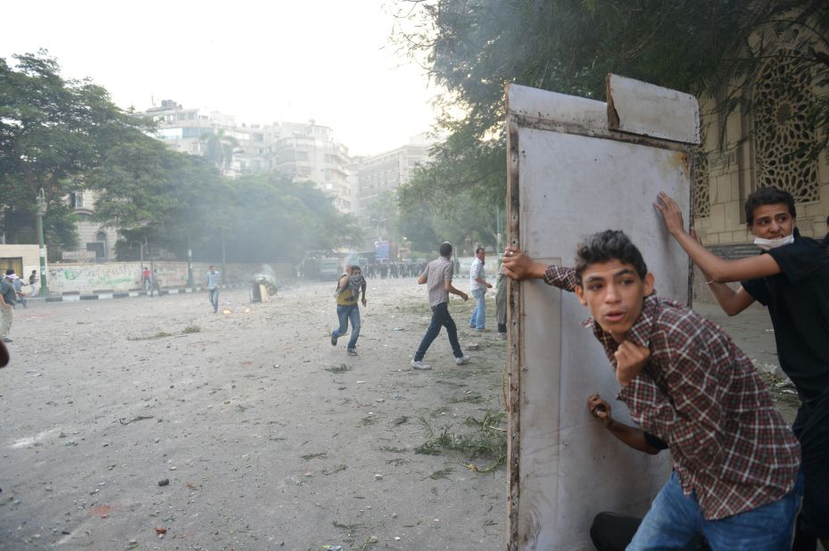 Egyptian protesters take cover during clashes with riot police on Thursday.