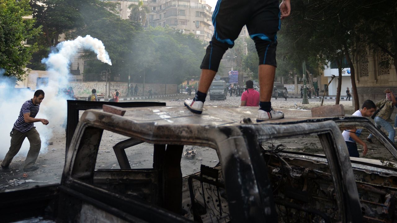 Egyptian protesters run for cover from tear gas fired by riot police during clashes on Thursday.