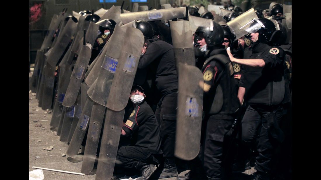  Riot police take cover from stones thrown by protesters on Thursday.