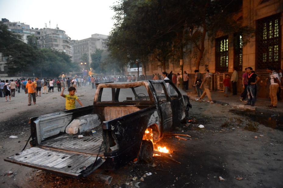A burned-out pickup sits between Egyptian protesters and riot police in Cairo on Thursday.