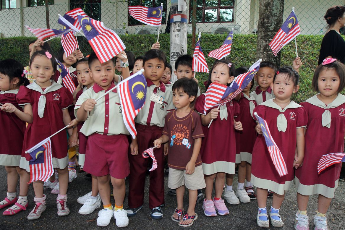Schoolchildren wave Malaysia national flags as Britain's Prince William and his wife Catherine, the Duchess of Cambridge, arrive at the Hospis Malaysia in Kuala Lumpur on September 13, 2012.